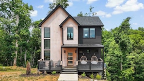 A two-story cabin with a deck, large windows, and a dark roof. - Family Friendly Getaway・Pool・Arcade・Hot Tub (Sevierville)