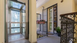 A corridor with a glass door leading to a balcony, a metal railing, and a potted plant. - I Vicini del Re by Wonderful Italy (Turin)