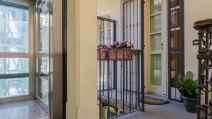 A modern building entrance with a glass door, a metal gate, and a small balcony with flowers. - I Vicini del Re by Wonderful Italy (Turin)