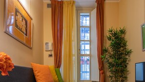 A cozy living room with a grey sofa, colorful cushions, a potted plant, a television, and a framed picture on the wall. - I Vicini del Re by Wonderful Italy (Turin)
