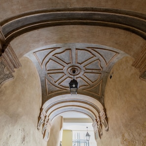 An arched corridor with a decorative ceiling and a hanging lantern.