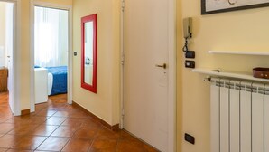 A hallway with a tiled floor, a white door, a red-framed mirror, and a painting on the wall. - Casa Vacanze Nostos Alabardieri by Napoliapartments (Naples)