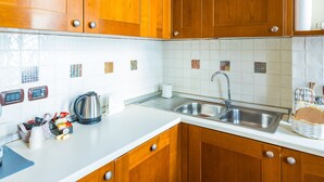 A kitchen with wooden cabinets, a white countertop, a stainless steel sink, and a tiled backsplash. - Casa Vacanze Nostos Alabardieri by Napoliapartments (Naples)