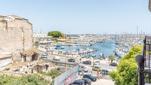 A marina with numerous boats docked, a historic building on the left, and a busy street in the foreground. - Oretea Apartment With Terrace by Wonderful Italy (Palermo)