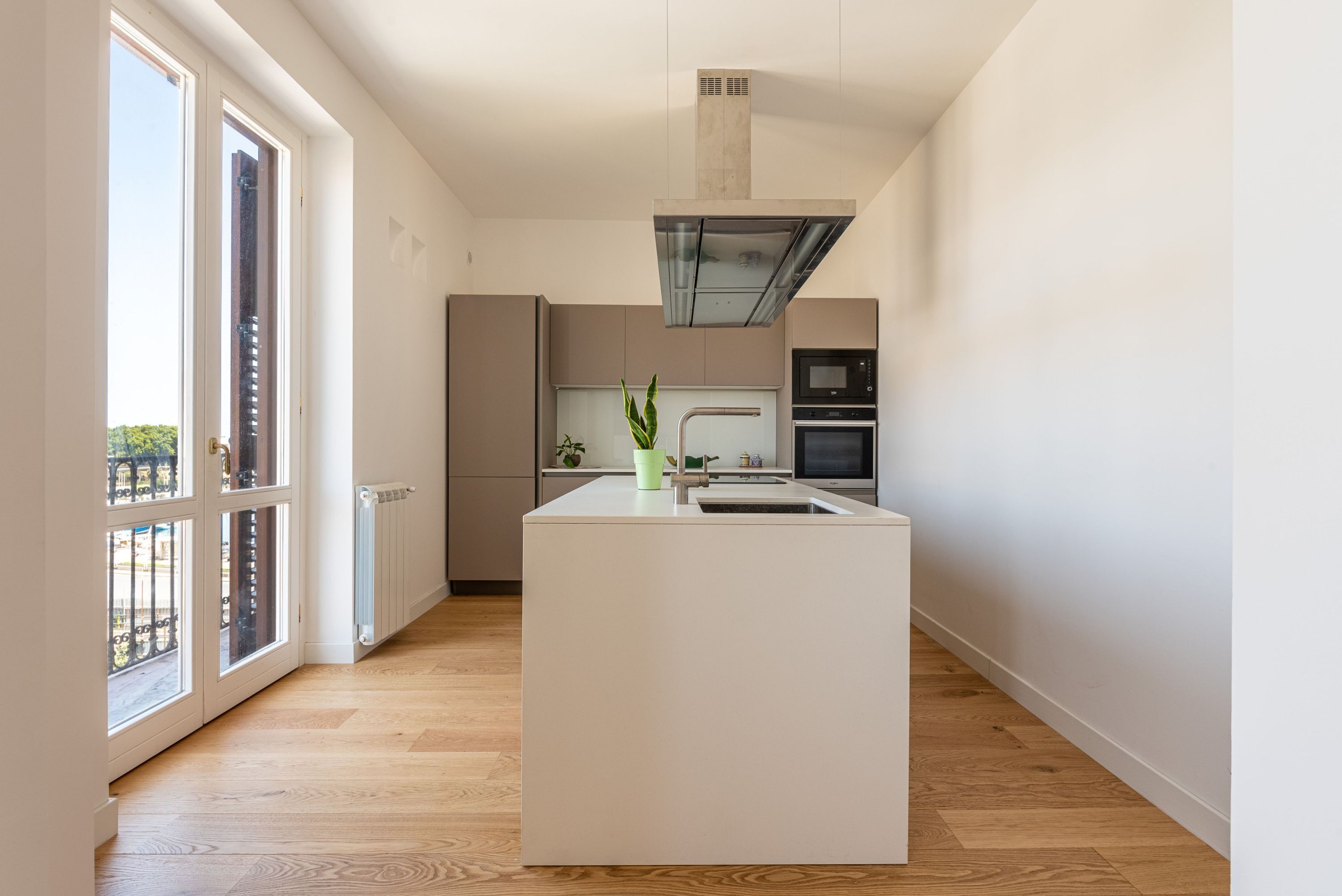 A modern kitchen with a central island, built-in appliances, and large windows.