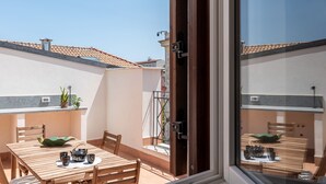 A wooden table with chairs and a small table lamp, a window with a view of a building, and a door with a handle. - Oretea Apartment With Terrace by Wonderful Italy (Palermo)