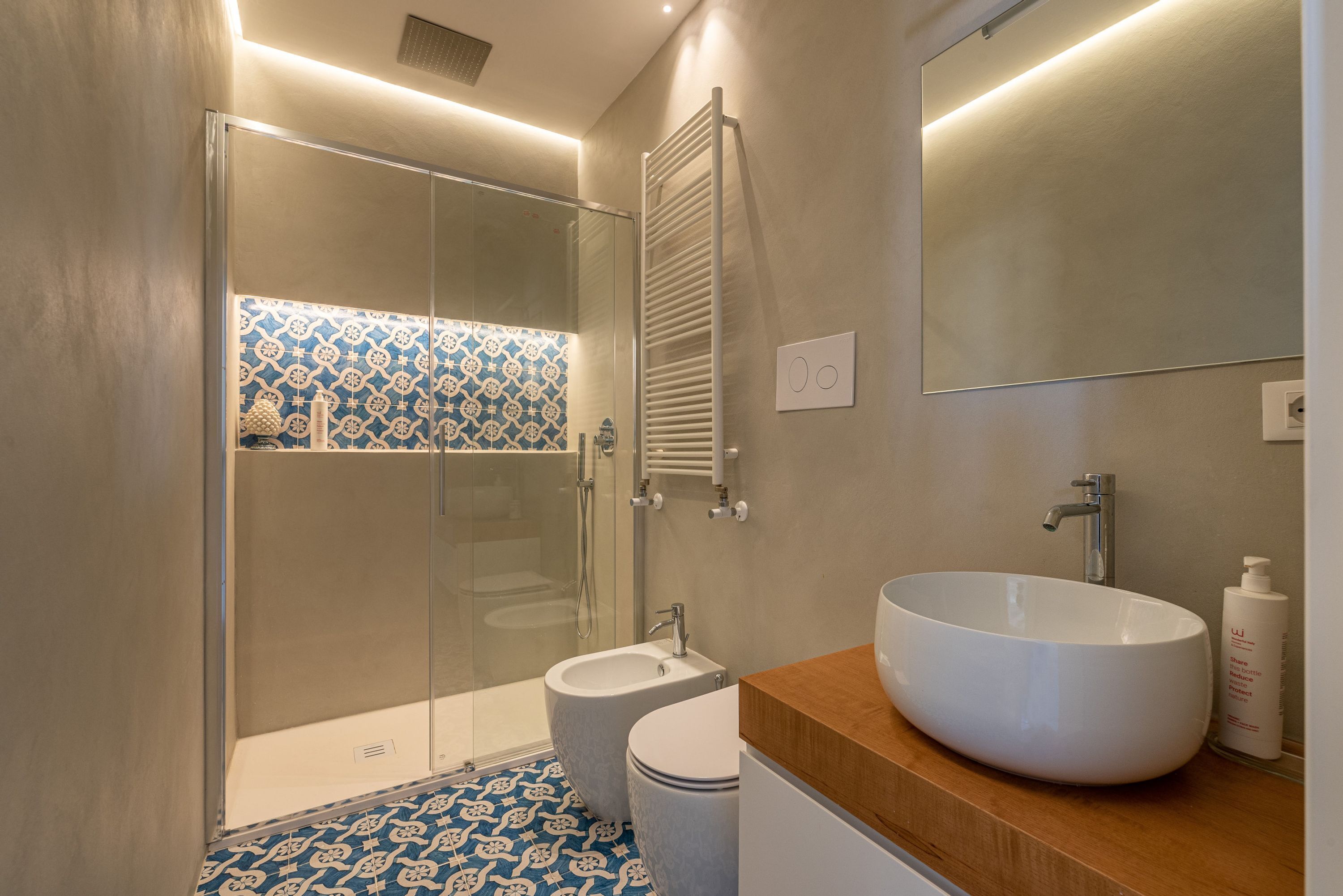 A modern bathroom with a glass-enclosed shower, a white sink, and a wooden vanity.
