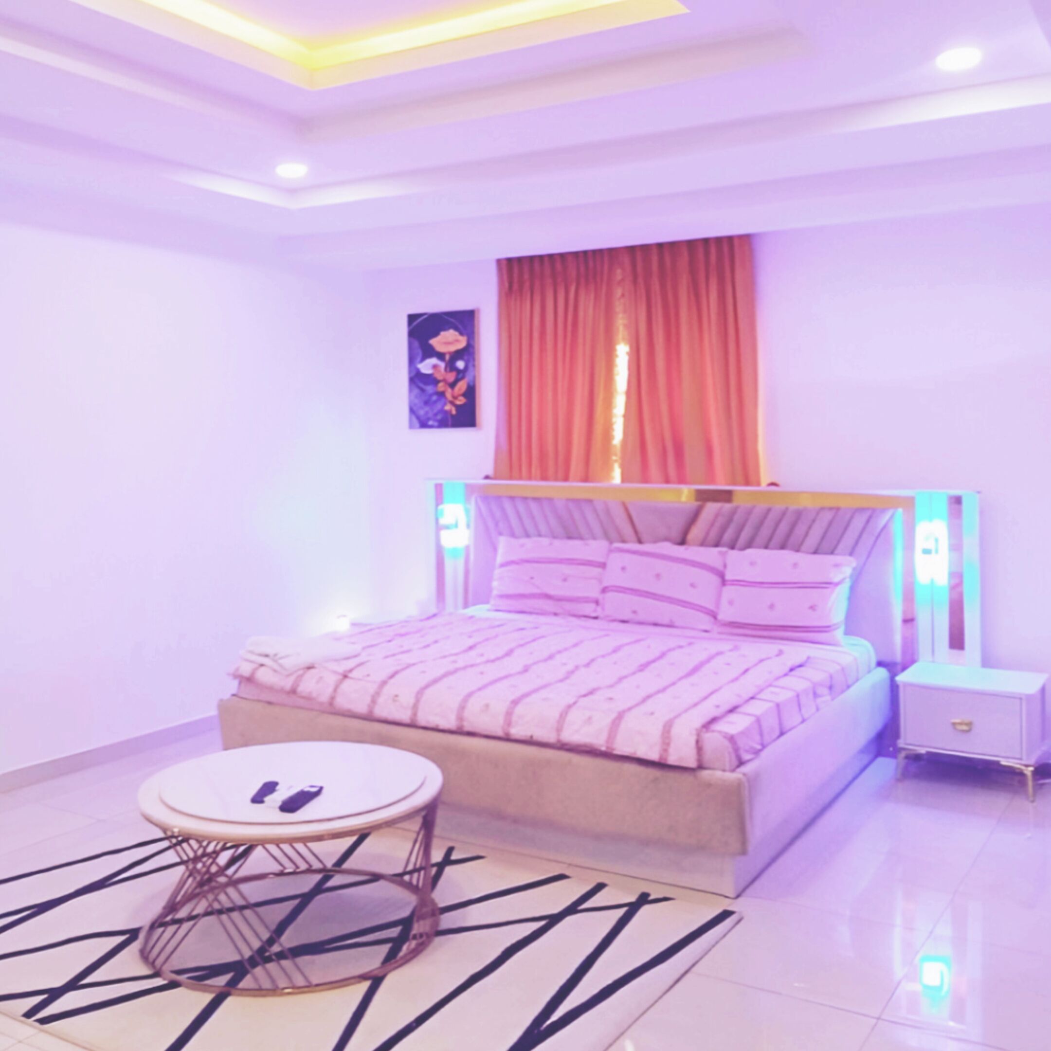 A bedroom with a bed, nightstand, and round table.