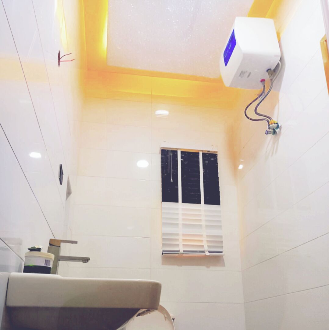 Une salle de bain avec des carreaux blancs, un lavabo, une fenêtre avec des stores et un luminaire au plafond.