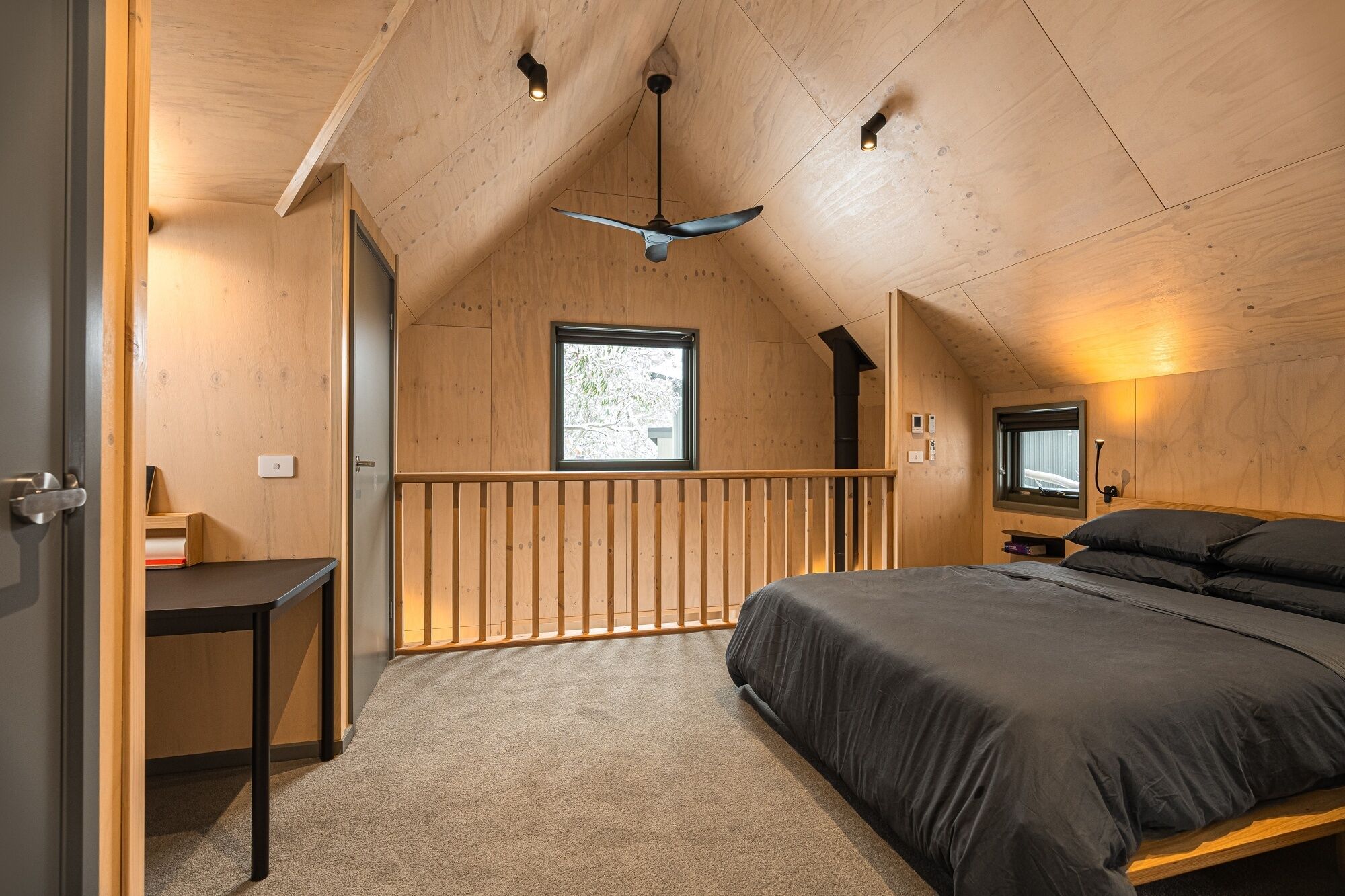 Ein gemütliches Schlafzimmer mit schrägen Wänden, einem Bett, einem Schreibtisch und einem Fenster.