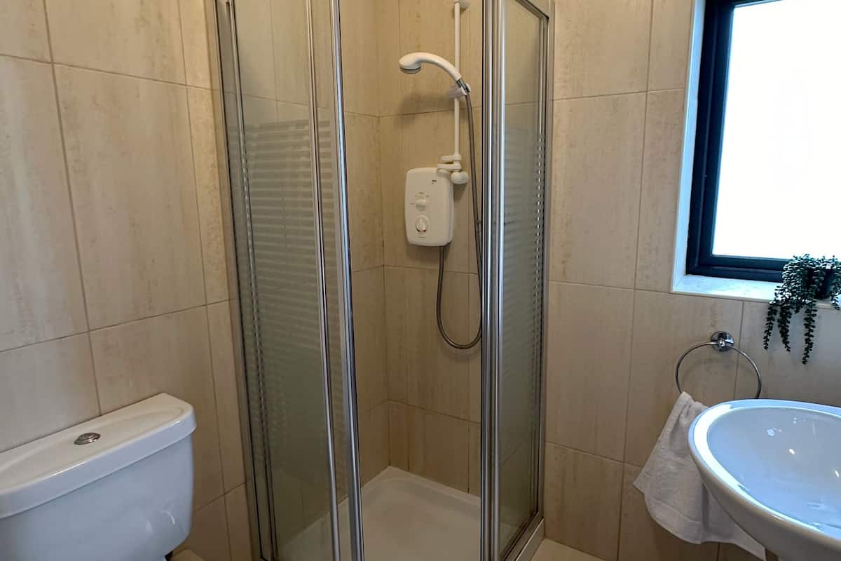 Une salle de bain avec une douche à parois de verre, des toilettes et un lavabo.