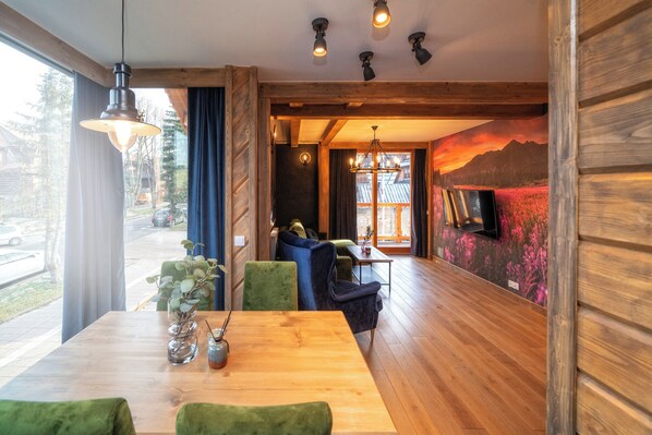 A wooden interior with a dining table, chairs, and a view of the outside. - Mountain Shelter Apartments (Zakopane)