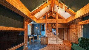 A spacious living area with a wooden ceiling, a green sofa, and a dining table. - Mountain Shelter Apartments (Zakopane)