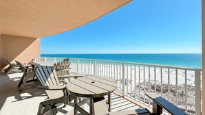 Un balcon avec vue sur la plage, comprenant une table et des chaises.