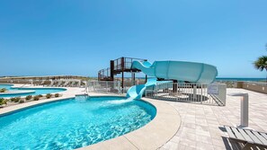 A pool with a water slide, lounge chairs, and a view of the ocean. - New Complex!  BeachFront!  Lazy River/Slide!!  Parking Level!! (Orange Beach)