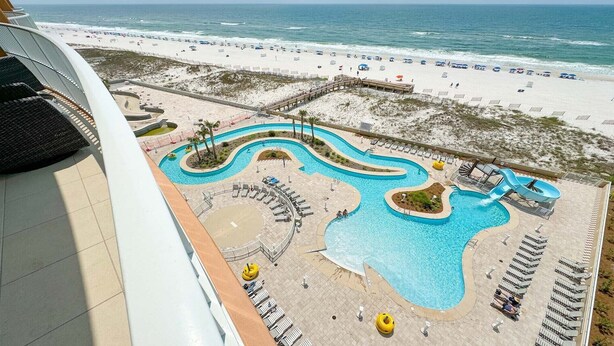 A resort with a large pool area, a beach, and a view of the ocean. - New Complex!  BeachFront!  Lazy River/Slide!!  Parking Level!! (Orange Beach)