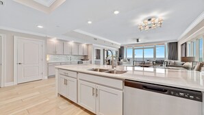 A spacious kitchen with a large island, white cabinetry, and a dishwasher. - New Complex!  BeachFront!  Lazy River/Slide!!  Parking Level!! (Orange Beach)