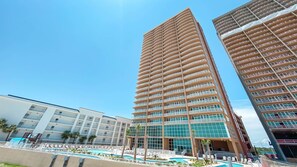 A high-rise hotel with multiple balconies, a swimming pool, and a modern architectural design. - New Complex!  BeachFront!  Lazy River/Slide!!  Parking Level!! (Orange Beach)