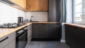 A modern kitchen with wooden cabinets, a stainless steel range, and a built-in oven. - RentPlanet - Apartament Malarska (Wroclaw)