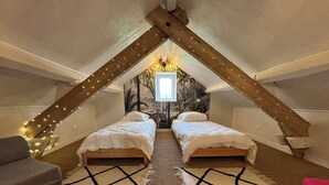 A cozy attic bedroom with two beds, a gray sofa, and a red chair. - "vers L'horizon" - Maison de Vacances à 800m de Cajarc Dans le Lot (Salvagnac-Cajarc)