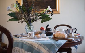 A dining table with a vase of flowers, a teapot, a coffee pot, and various breakfast items. - Duomo Suite - Two Bedroom Apartment, Sleeps 4 (Firenze)