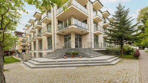 Ein mehrgeschossiges Gebäude mit einer zentralen Treppe, Balkonen und Blumentöpfen.