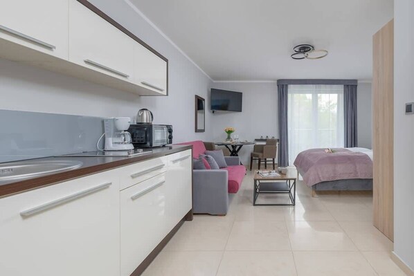 A modern kitchen with white cabinets, a coffee machine, and a dining area with a table and chairs.