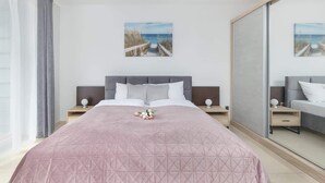 Ein Hotelzimmer mit einem großen Bett, zwei Nachttischen, einem Spiegel und Blick auf den Strand.
