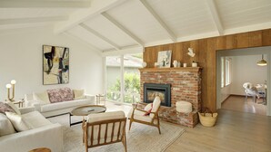 A spacious living room with a fireplace, a large window, and a view of the outdoors.