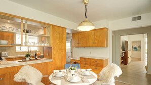 A modern kitchen with wooden cabinets, a dining table set for four, and a clear view into the adjacent dining area.