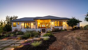 Une maison moderne à deux étages, dotée d’un porche avant couvert, de grandes fenêtres et d’un jardin aménagé.