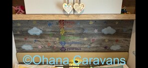 A child's bed with a wooden headboard decorated with clouds and stars, and a heart-shaped sign with a unicorn and a message. - Silver 3 Bedroom Caravan Located at Seton Sands H (Prestonpans)