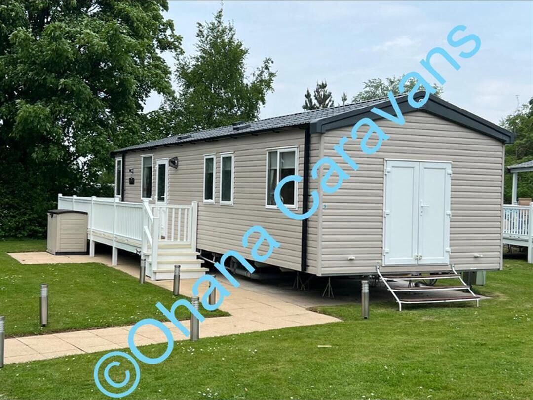 A mobile home with a porch, a small deck, and a ramp for accessibility.