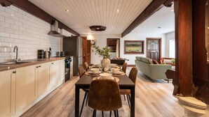 Una cocina moderna con azulejos blancos tipo metro, armarios de madera y un comedor con mesa y sillas de madera.