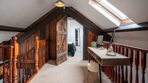 Dormitorio estilo loft con techo inclinado, escalera de madera y tragaluz.