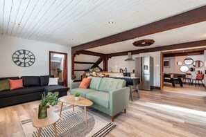 A spacious living area with a sofa, coffee table, and a dining table. A kitchen is visible in the background.