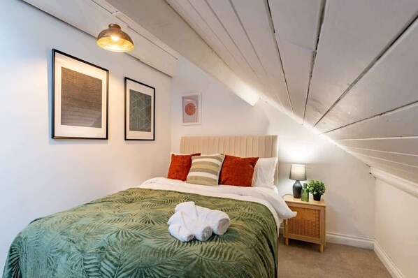 Une chambre à coucher avec un lit, une table de chevet avec une lampe et des tableaux encadrés accrochés au mur.