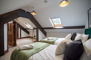 Un dormitorio con dos camas, un tragaluz y una viga de techo de madera.