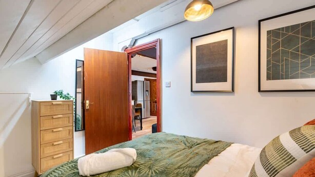 Un dormitorio con una cama, un aparador de madera y una puerta que da a otra habitación.