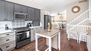 Una cocina moderna con armarios grises, una estufa de acero inoxidable y una mesa de comedor de madera.