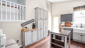 Una cocina con barra de café, armarios de madera y una zona de comedor con mesa y sillas.
