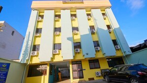 A multi-story building with a yellow facade, air conditioning units, and a sign indicating it is a hotel. - TOMEDI HOTEL  (Douala)