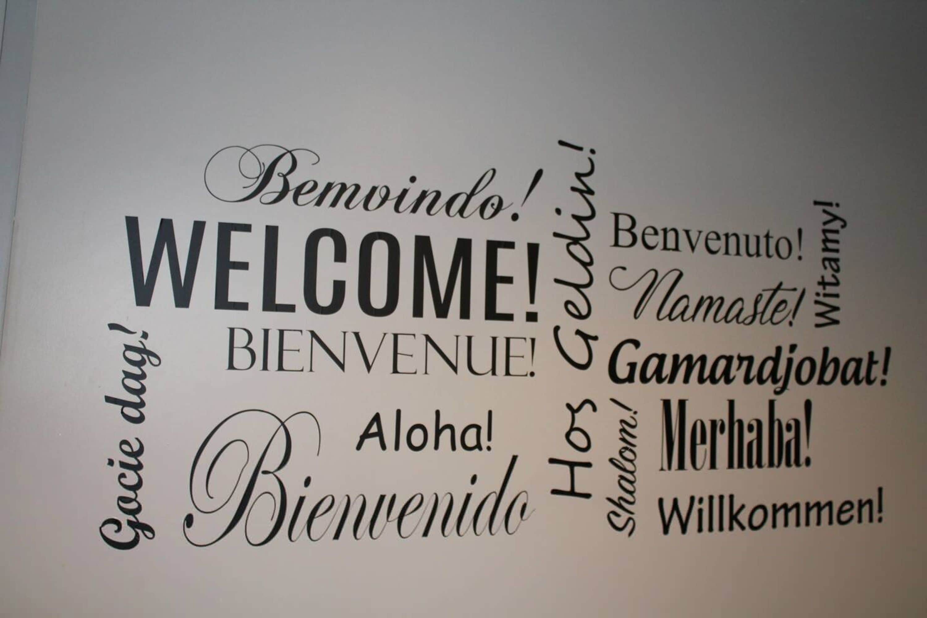 Un mur orné de différentes formules d’accueil dans plusieurs langues.
