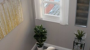 A staircase with a white railing, a window with white trim, and a potted plant on the landing. - 4 Bed Boutique House Lisburn Road (Belfast)