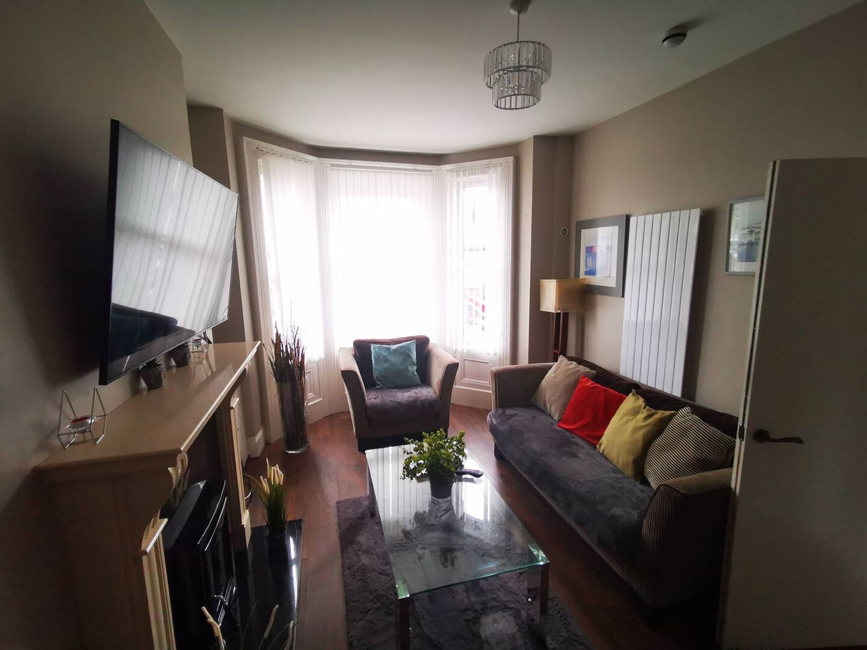 A living room with a flat-screen TV, a sofa, a coffee table, and a fireplace.