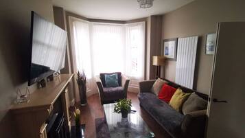 A living room with a flat-screen TV, a sofa, a coffee table, and a fireplace.