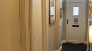 A hallway with closed doors, a carpeted entrance, and a door with a fire exit sign. - 4 Bed Boutique House Lisburn Road (Belfast)