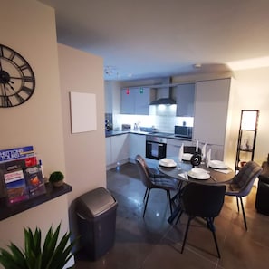 Une cuisine moderne avec un coin repas, une poubelle et une horloge au mur.