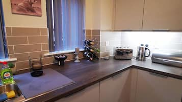 A compact kitchen with a window, a toaster, a kettle, and a first aid box sign.