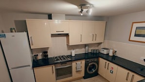 Eine kompakte Küche mit Kühlschrank, Herd, Backofen und Waschmaschine.